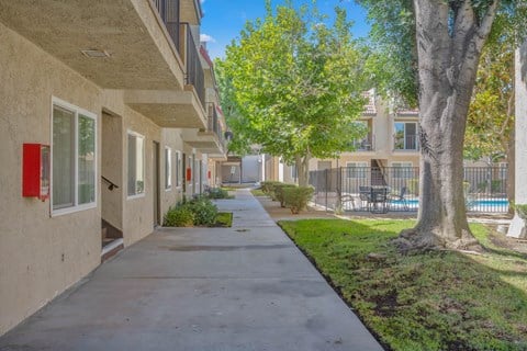 a sidewalk in front of a building with trees