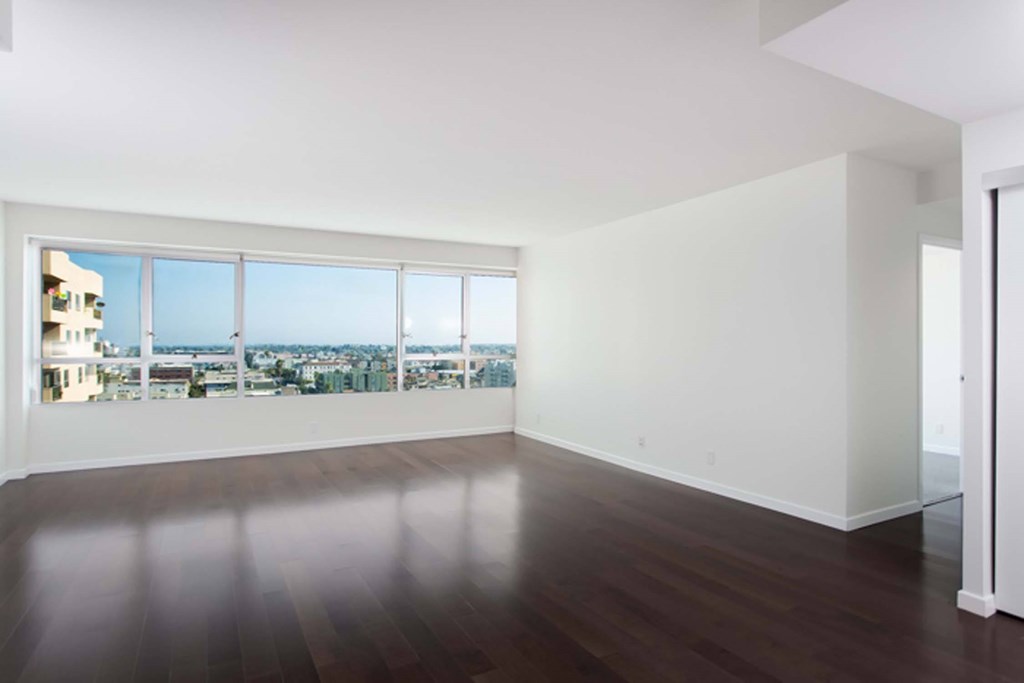 A large empty room with a view of the city through the windows.