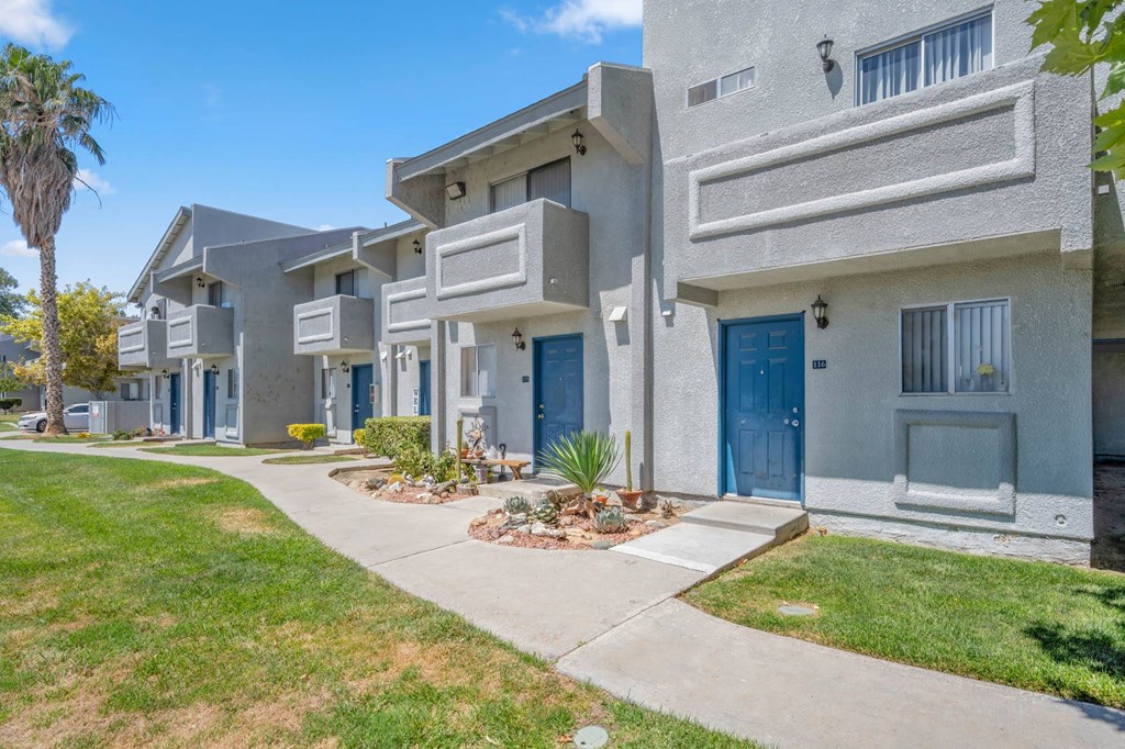 a row of townhomes with blue doors and grass and a sidewalk