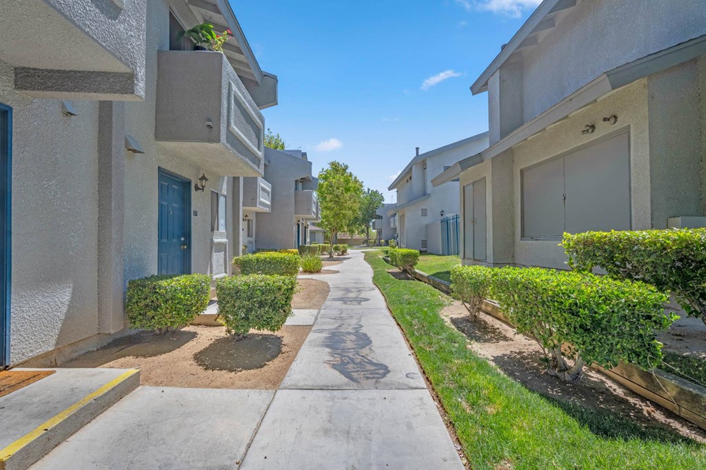 a view of an apartment complex with a sidewalk and grass