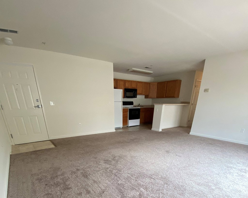 American Square Apartments - 55+ Community -  Living room / Kitchen / Wall-to-wall carpet