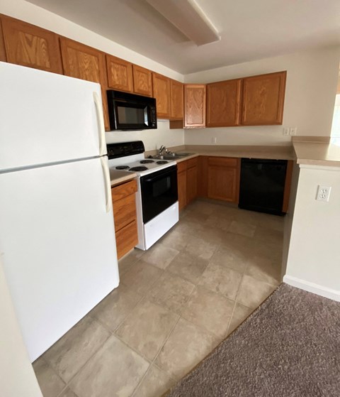 an empty kitchen with white appliances and wooden cabinets