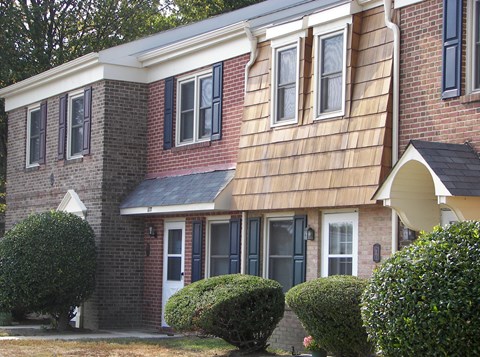 the front of a brick house with wood siding