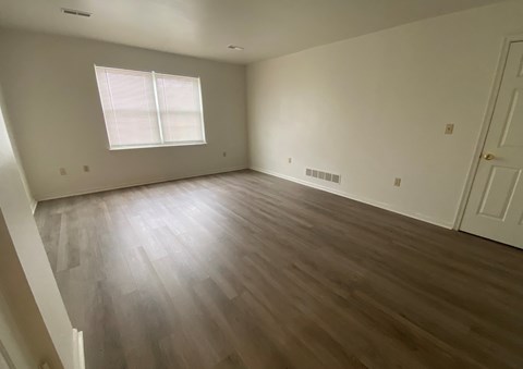an empty living room with wooden floors and white walls