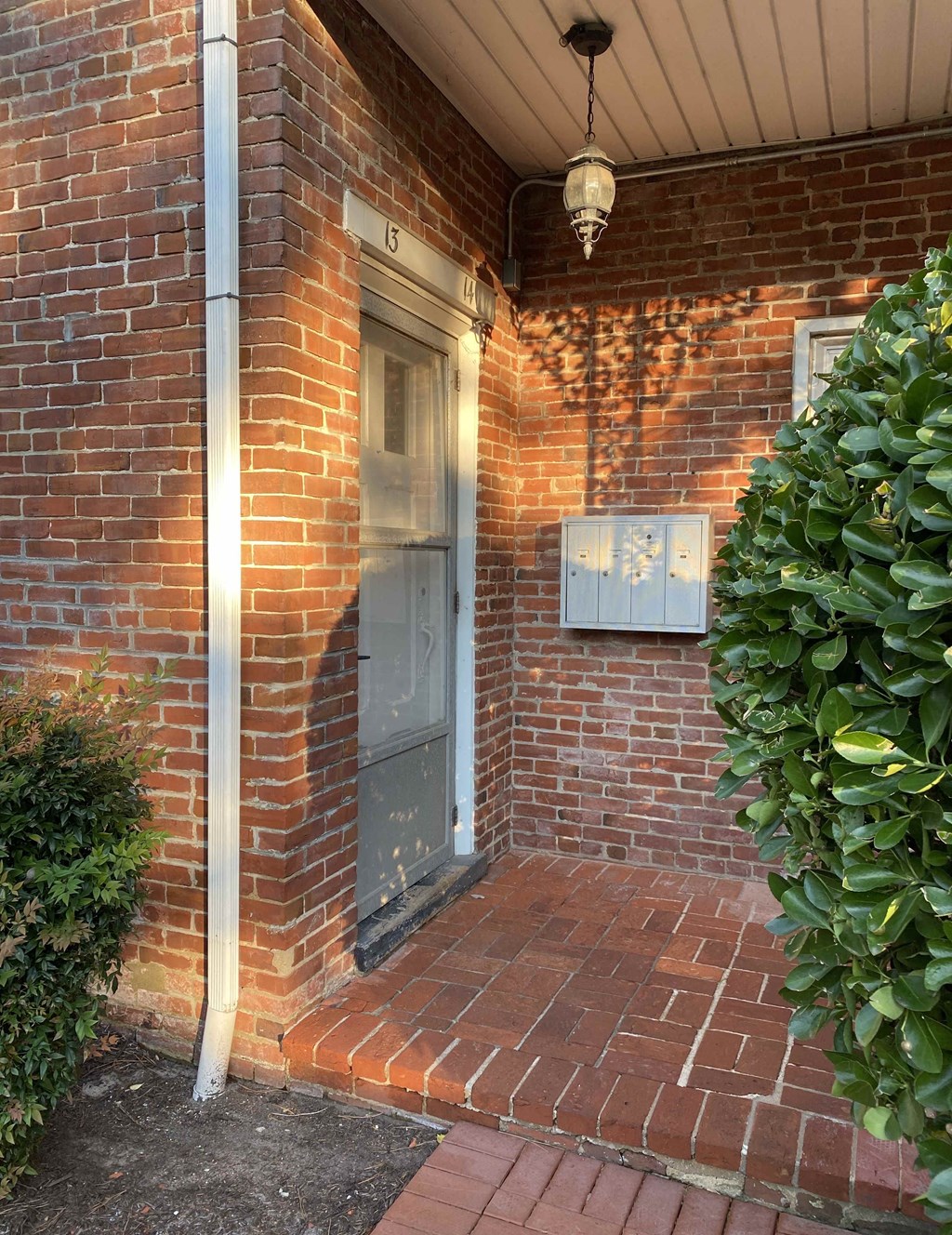 a front door of a brick house with a mailbox on the side of the house