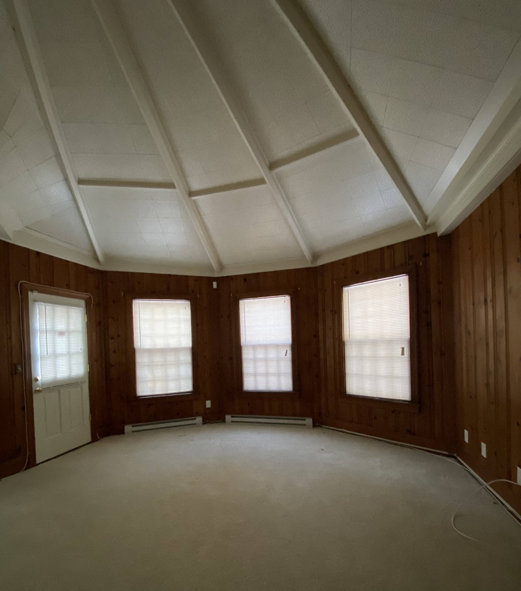Kings Court Apartments - Front House - Den / Wood-paneled walls / Vaulted, wood-paneled ceiling / Door to brick patio / Wall-to-wall carpet