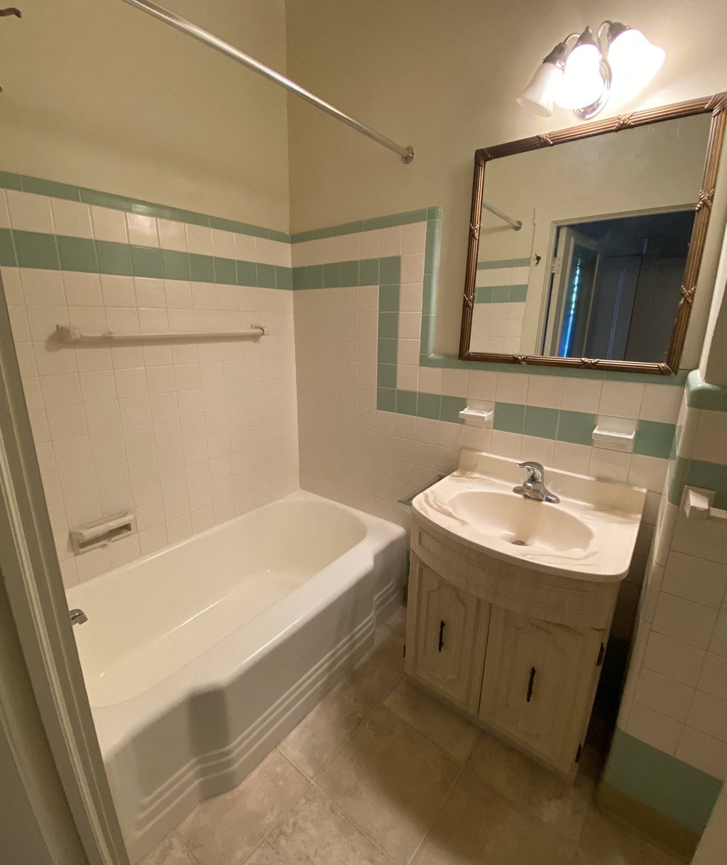 Kings Court Apartments - Front House - Full bath with tub / vanity / mirror / tiled walls / vinyl flooring