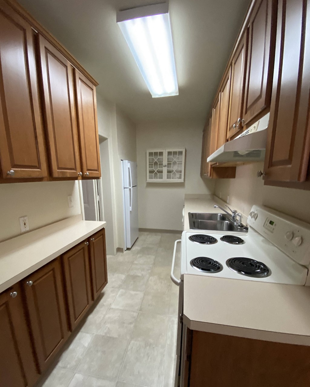 Kings Court Apartments - Front House - Kitchen (Galley-style) / Electric range / Range Hood / Dishwasher / Refrigerator / wood-grain cabinets / vinyl flooring