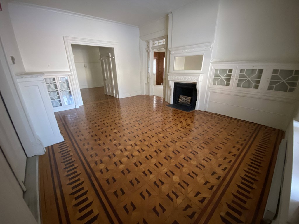 Kings Court Apartments - Front House - Living room / Wood Parquet flooring / Fireplace with Mantel / Built-in, glass-front cabinets / Stained glass transom windows