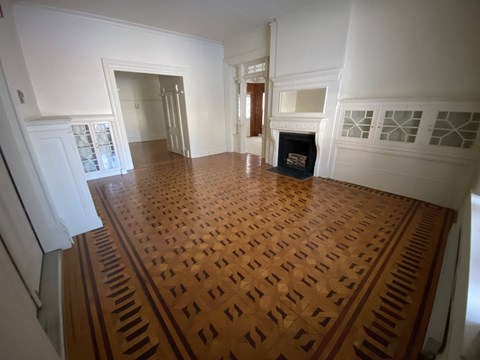 Kings Court Apartments - Front House - Living room / Wood Parquet flooring / Fireplace with Mantel / Built-in, glass-front cabinets / Stained glass transom windows