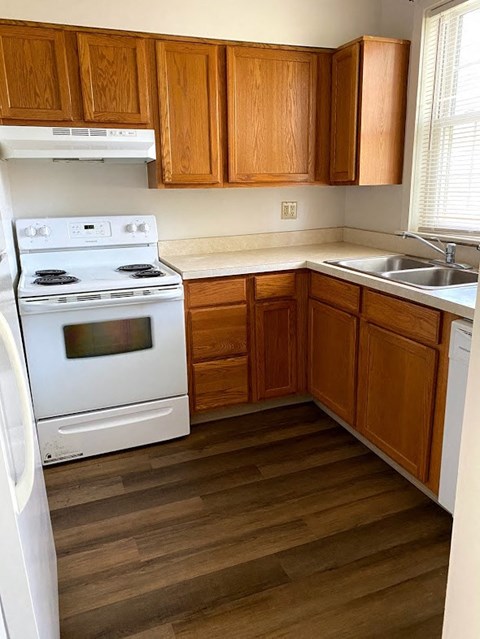 Garden Court Apartments - Kitchen / Electric Range, Sink, Garbage Disposal / Wood-grain cabinets / Wood-grain vinyl plank flooring
