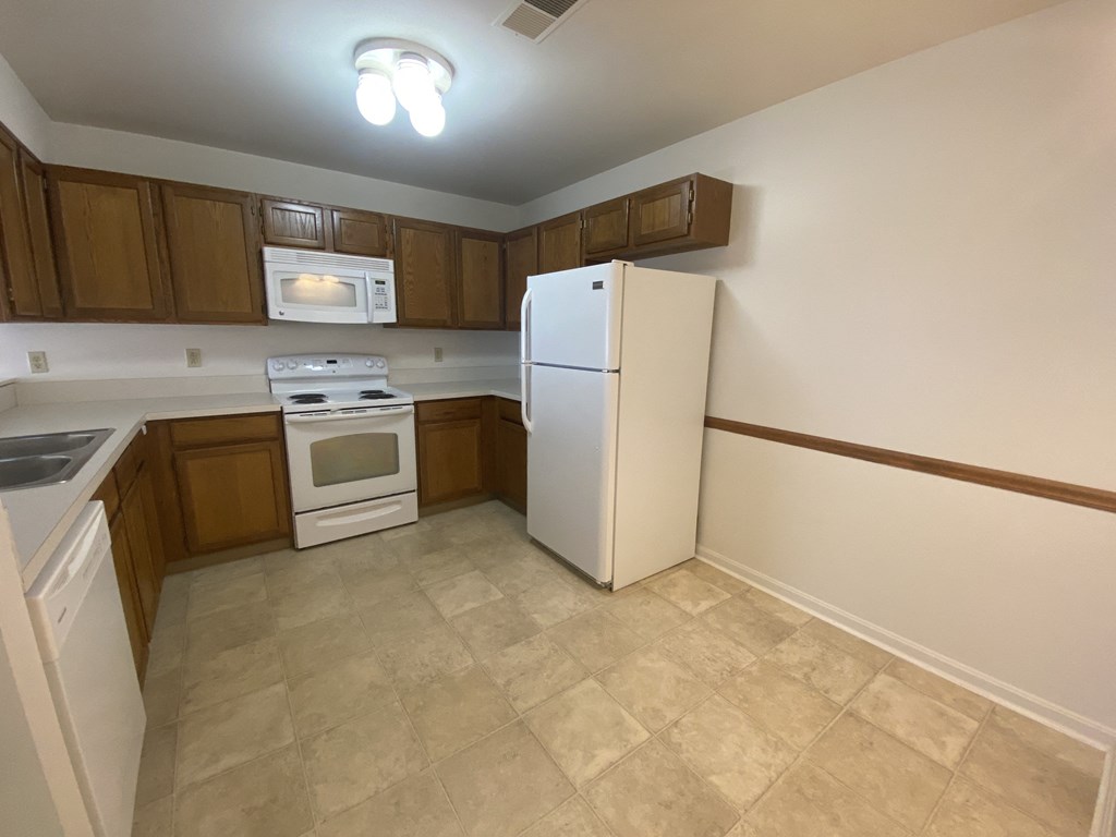 Kings Court Apartments - Main Building - Kitchen / Electric Range / Built-in Microwave / Dishwasher / Refrigerator / Wood-grain cabinets / Vinyl Flooring