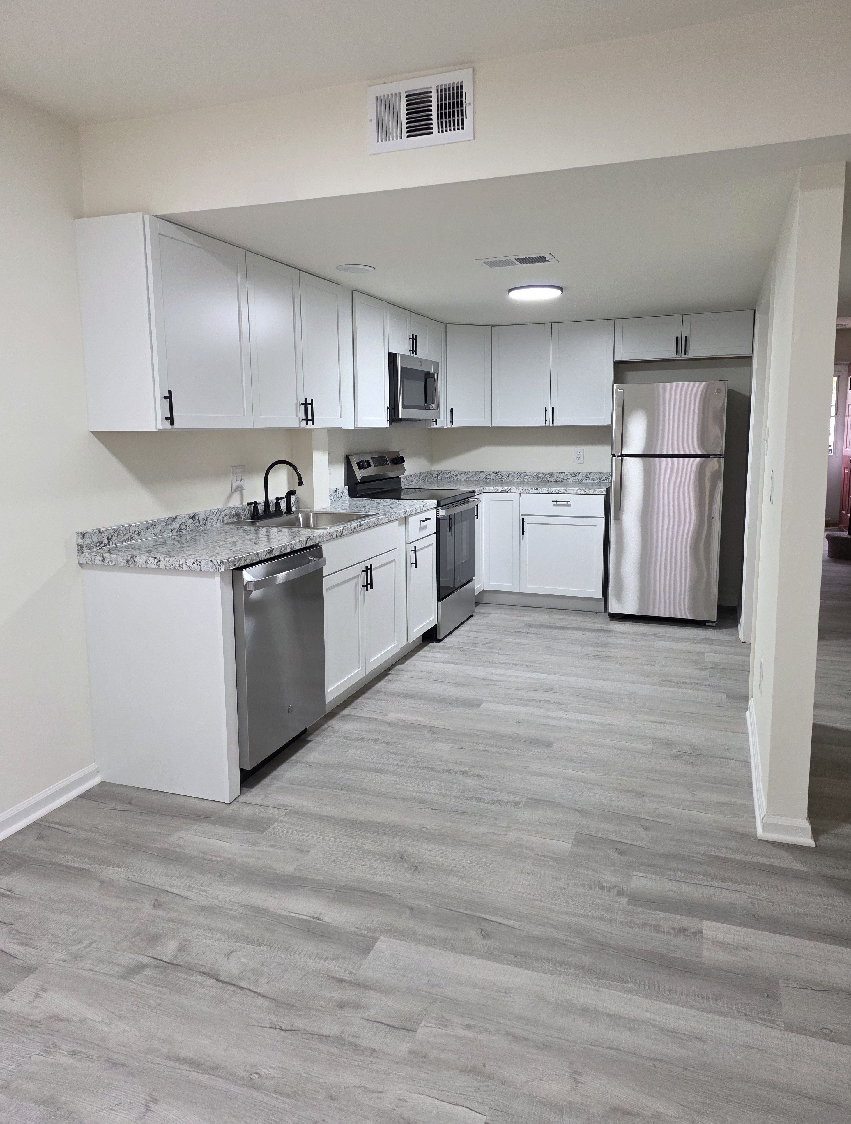 A kitchen with white cabinets and a marble countertop.