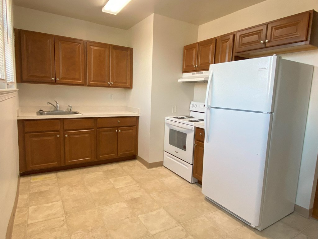 a kitchen with a white refrigerator freezer next to a stove top oven