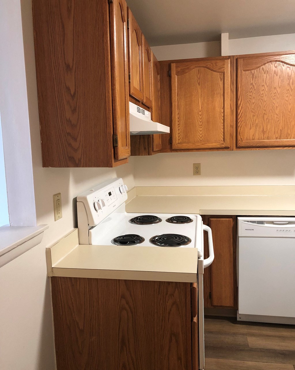 Loockerman Square Apartments - Kitchen with Electric range / Range hood / Dishwasher / Wood-grain cabinets / Pass-thru window to living room
