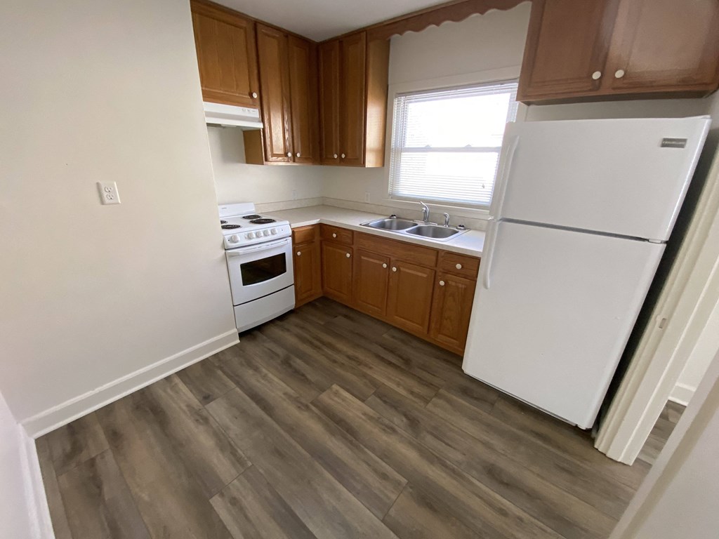 Mitten Apartments - Kitchen with window / Electric range / Range Hood / Refrigerator / Wood-grain, vinyl plank flooring