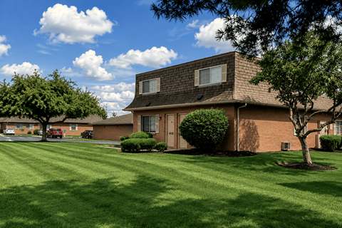 A house with a brown roof and a green lawn in front.