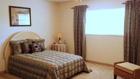 A bedroom with a bed, nightstand, and chair.