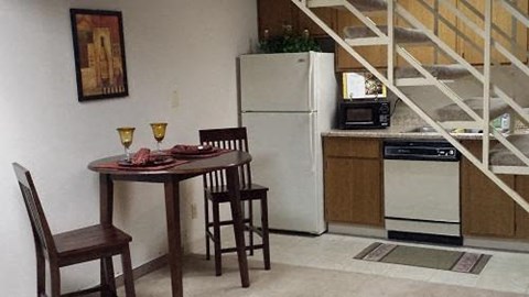 A kitchen with a table and chairs and a refrigerator.