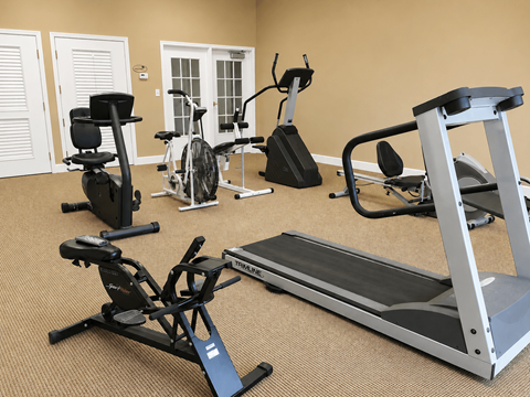 A home gym with a treadmill, stationary bike, and rowing machine.