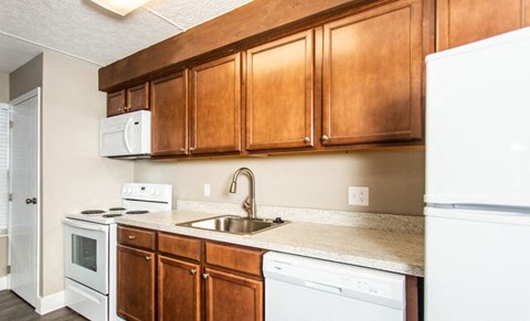 A kitchen with brown cabinets and white appliances.