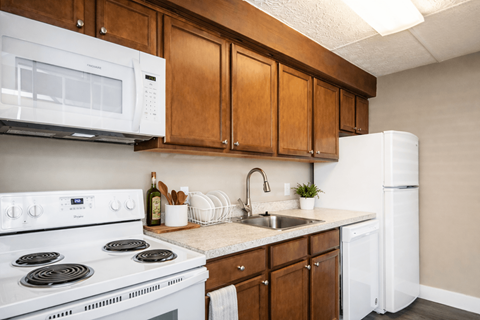 A kitchen with white appliances and wooden cabinets.