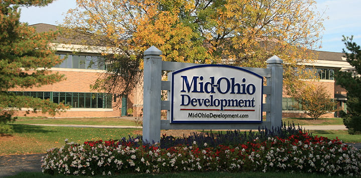 a sign in front of a building with flowers