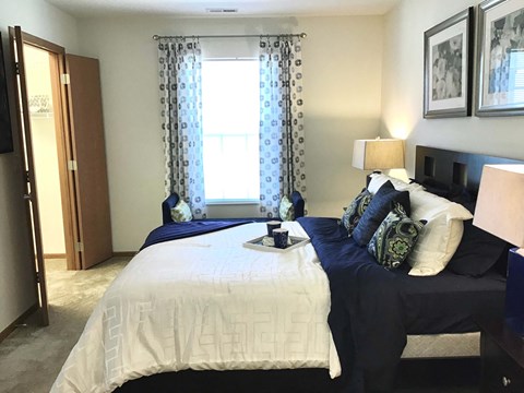 A bedroom with two beds and a nightstand with a lamp.