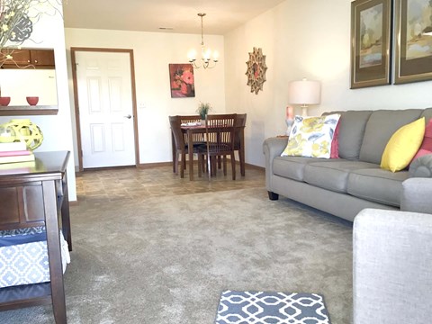A living room with a grey couch and a dining table with chairs.