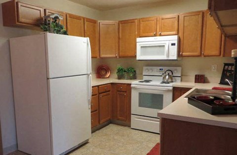 A kitchen with a white refrigerator and wooden cabinets.
