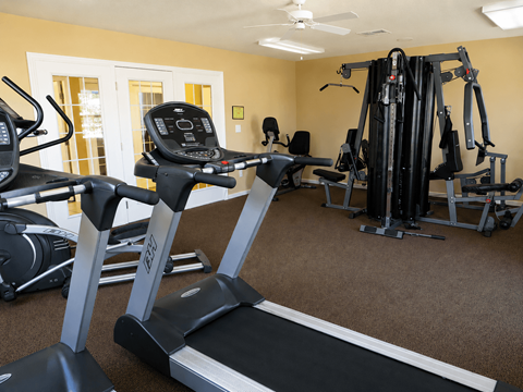 A home gym with treadmills, elliptical machines, and other exercise equipment.