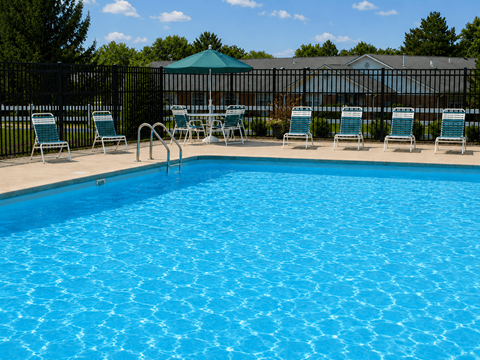 A pool with blue water and chairs around it.