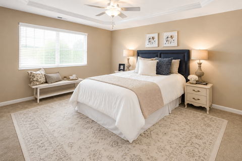 A bedroom with a large bed and a window with blinds.