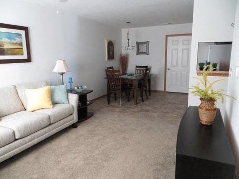 A living room with a couch, a table, a lamp, a plant, and a painting on the wall.