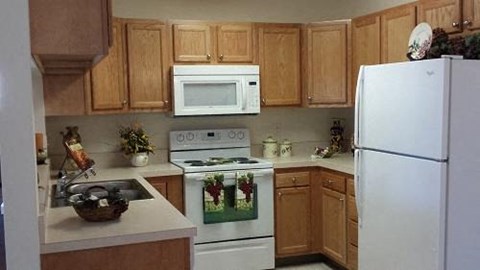 A kitchen with a white refrigerator, white oven, white microwave, and white sink.