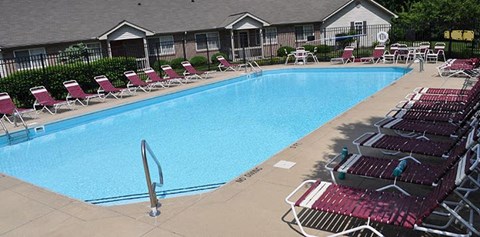 A swimming pool surrounded by red chairs.