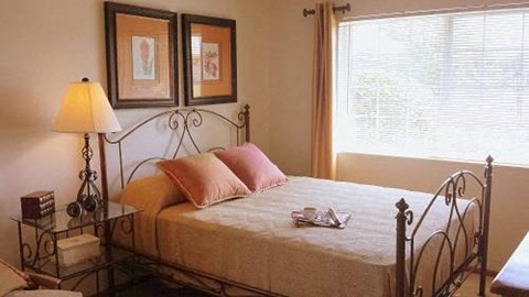 A bedroom with a bed, a lamp, and two pictures on the wall.