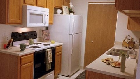A kitchen with a white refrigerator and wooden cabinets.