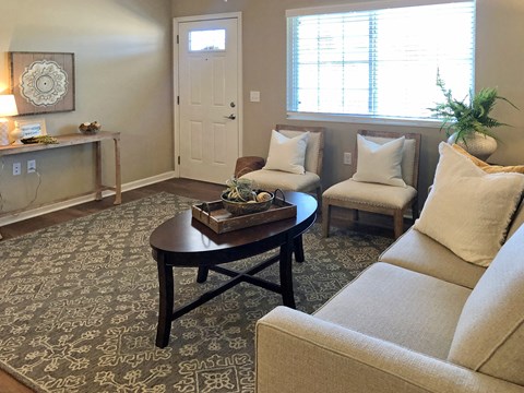 A living room with a couch, coffee table, and a window.