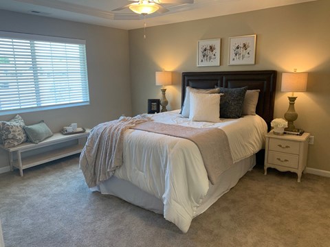 A bedroom with a large bed and a window with blinds.