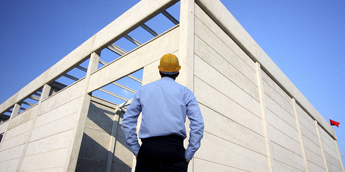 a construction worker looking at the side of a building