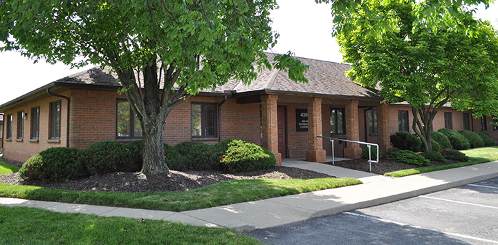 a small brick building with a tree in front of it