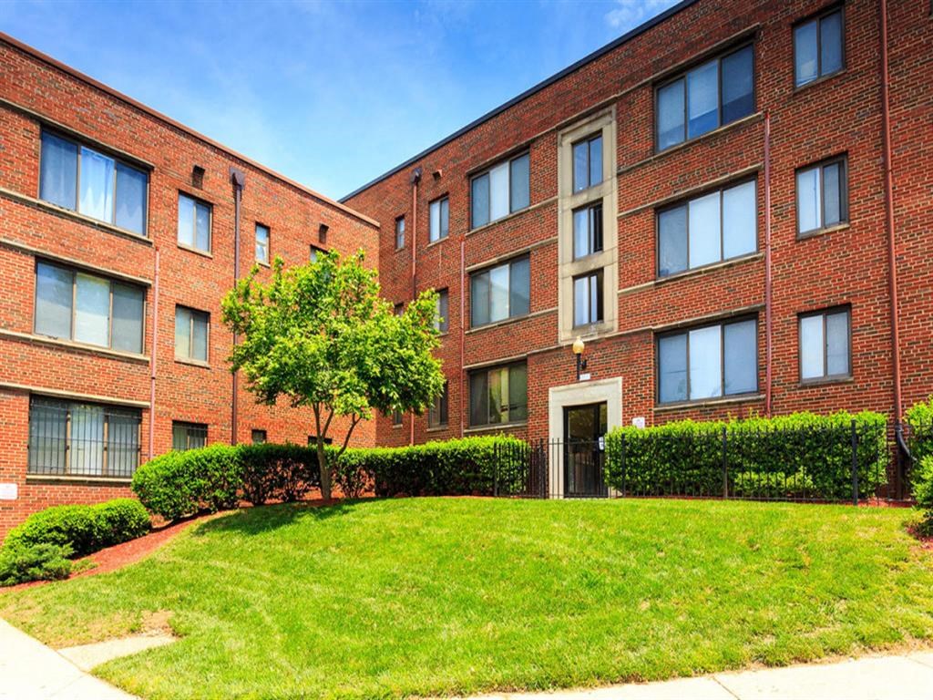 a red brick apartment building with a green lawn in front