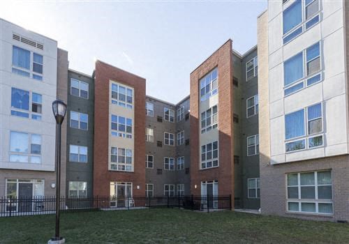 a row of apartment buildings with a green yard
