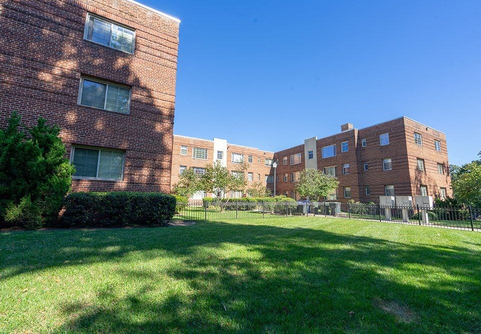 a group of brick apartment buildings on a green lawn