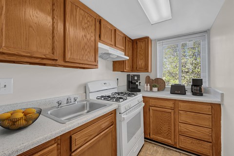 A kitchen with wooden cabinets and a white stove top oven.