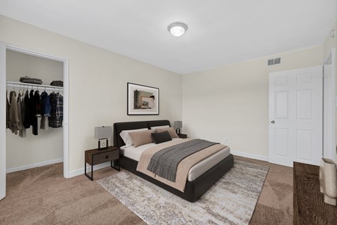 A bedroom with a large bed and a closet with clothes hanging.