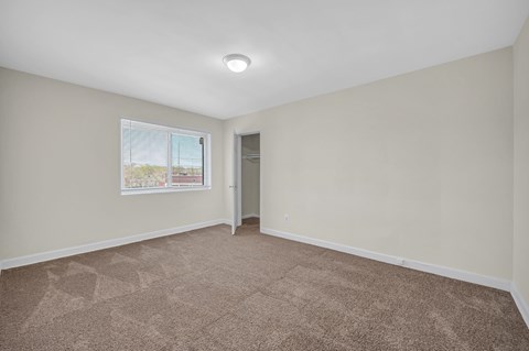 A room with a carpeted floor and a window.