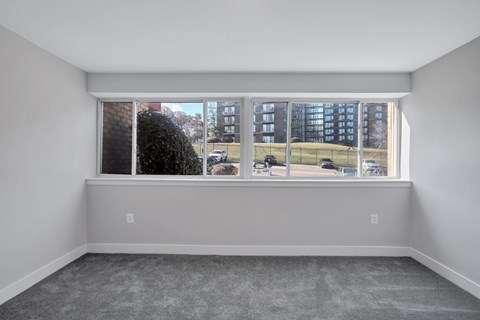 A room with a large window overlooking a parking lot and buildings.
