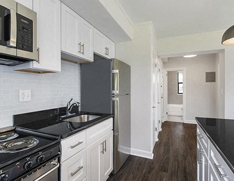 A kitchen with black countertops and white cabinets.